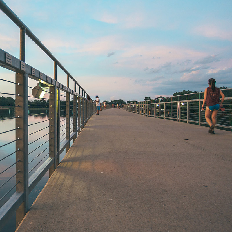 Drake student walking on the pedestrian bridge over Raccoon River near downtown Des Moines