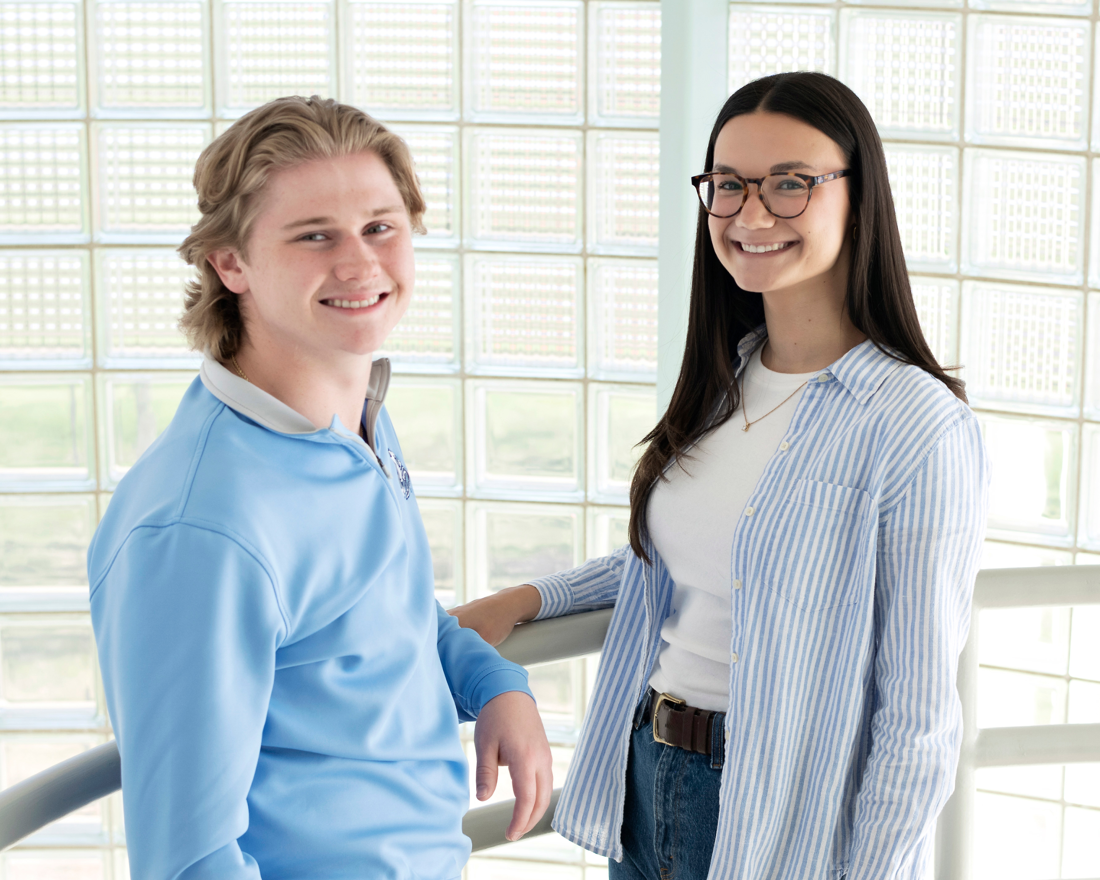 Two Drake students stand facing each other in a room where light passes through glass bricks