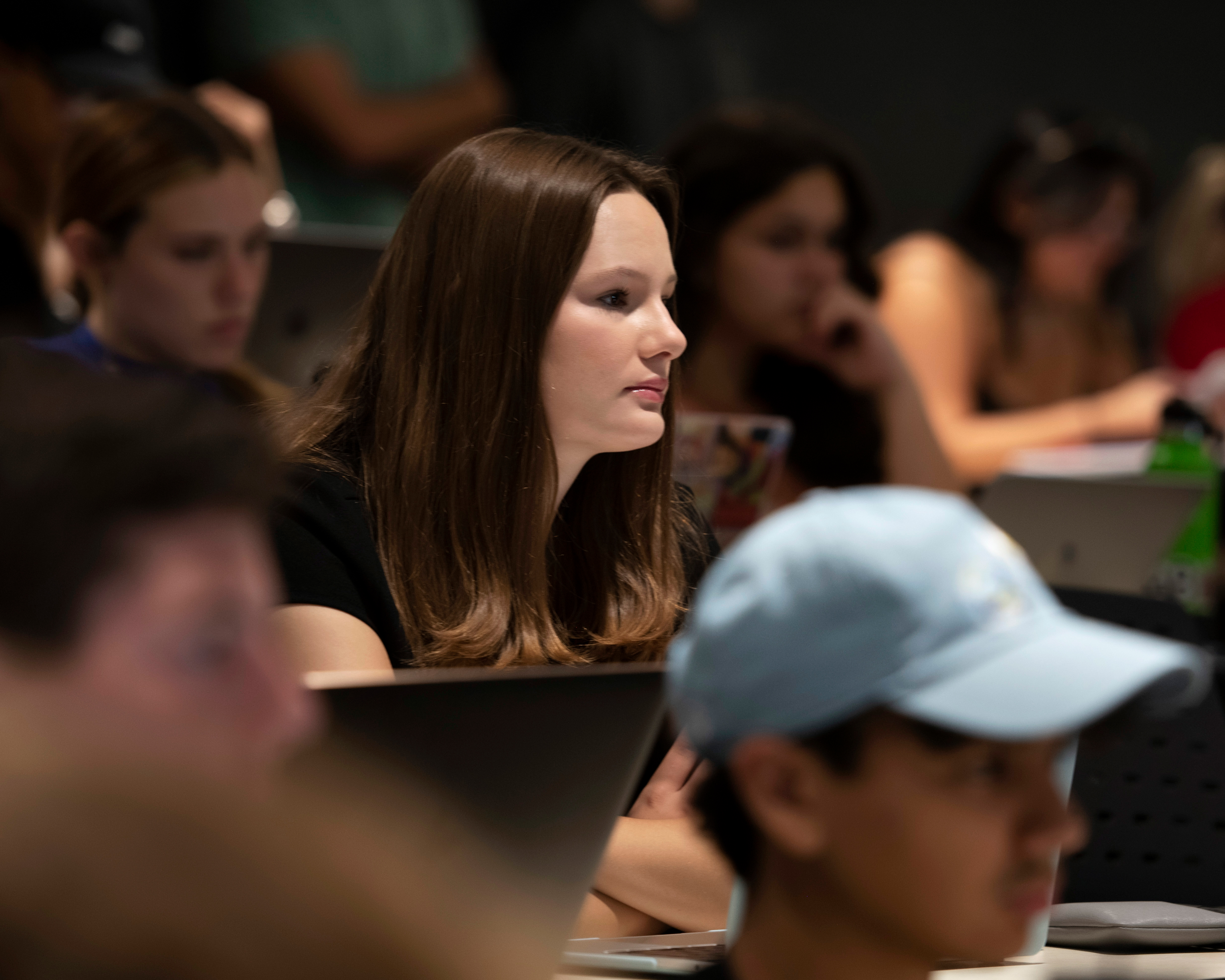 In a lecture hall, Drake students with their open laptops focus on a faculty member's lesson