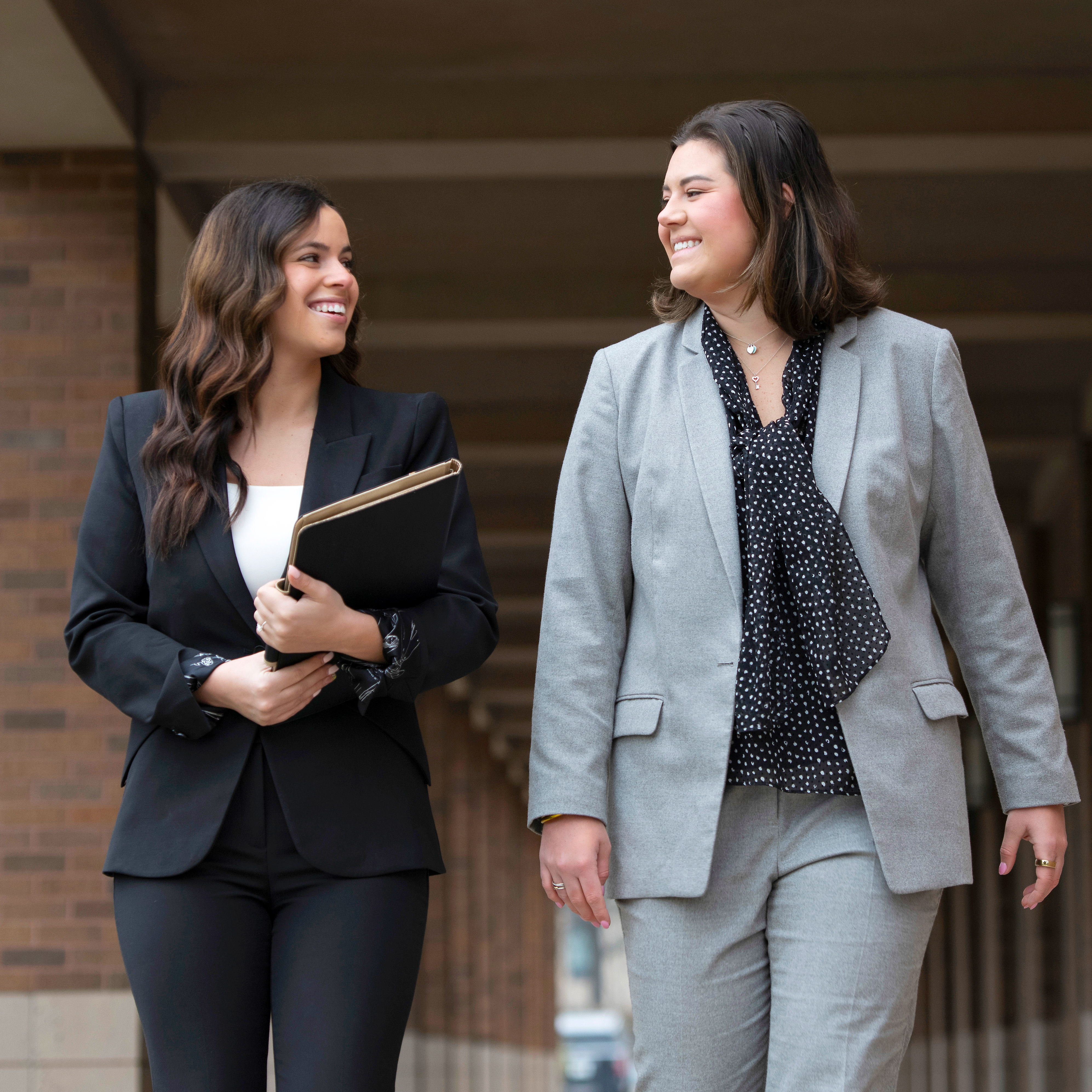 Two Drake Law students in suits converse as they wander through campus