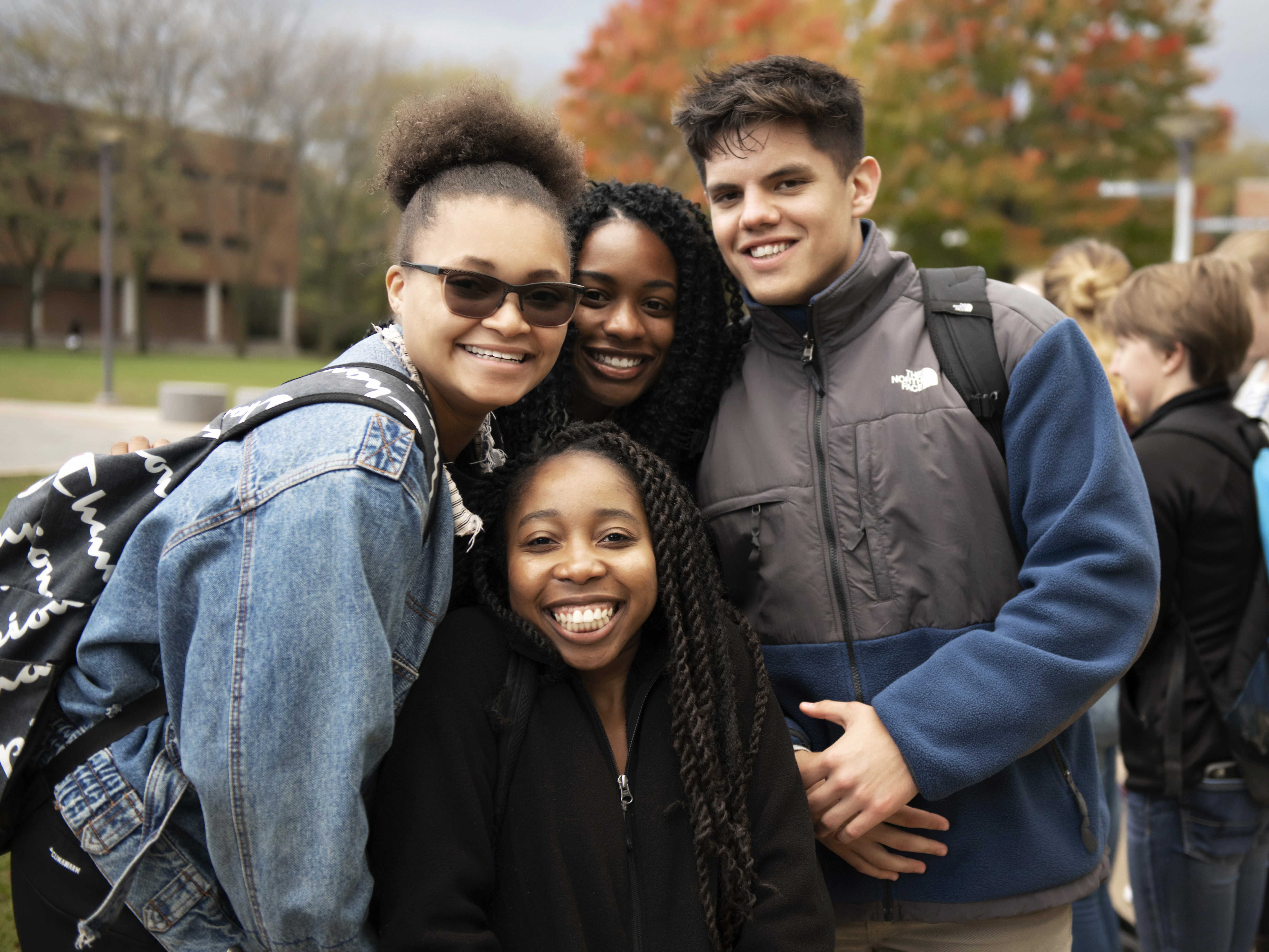 A group of Drake students in jackets huddle together on an early fall day