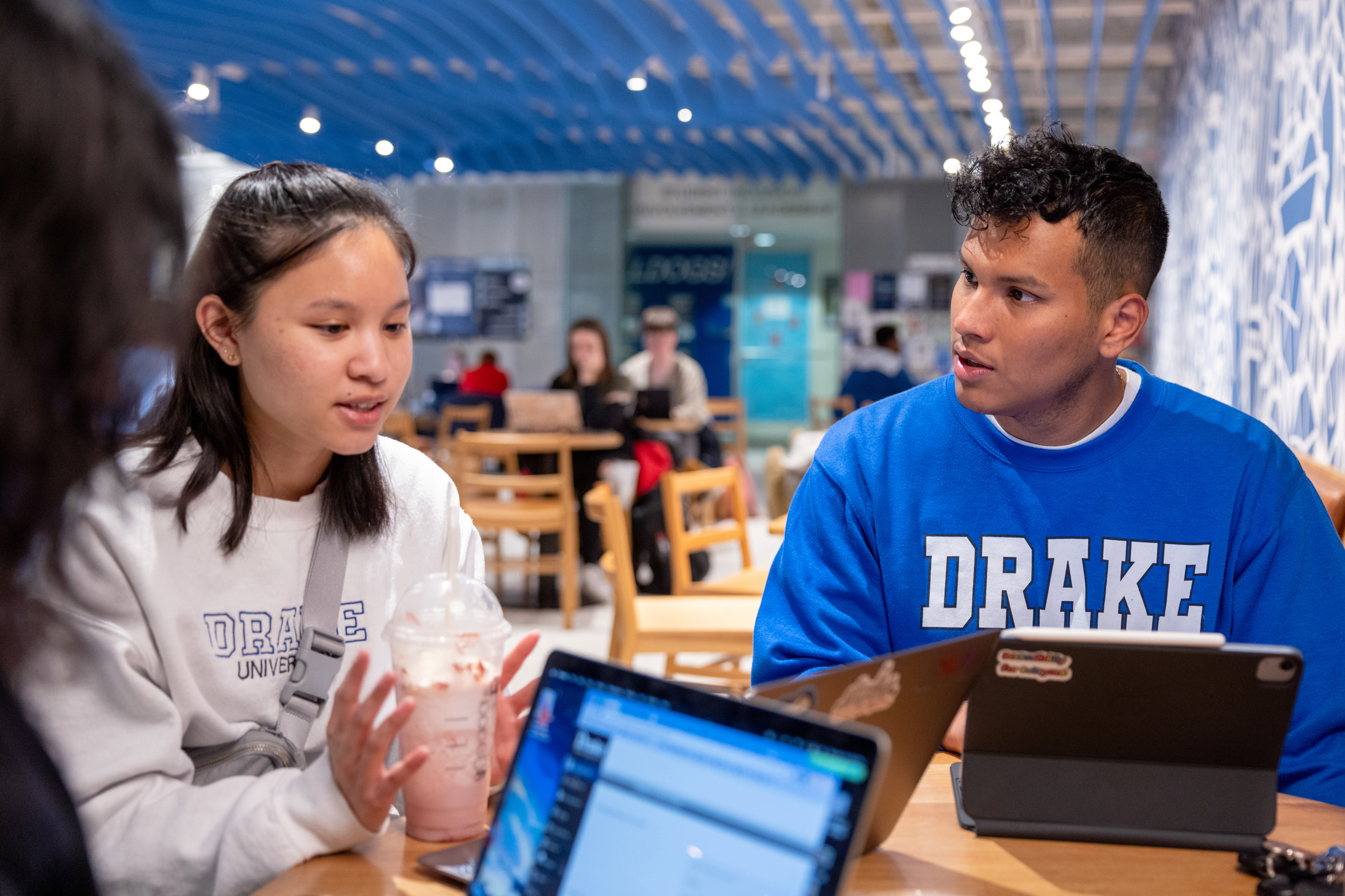 Sitting around a wooden table with laptops, a group of Crew Scholars hold a meeting in a dining area on Drake's campus