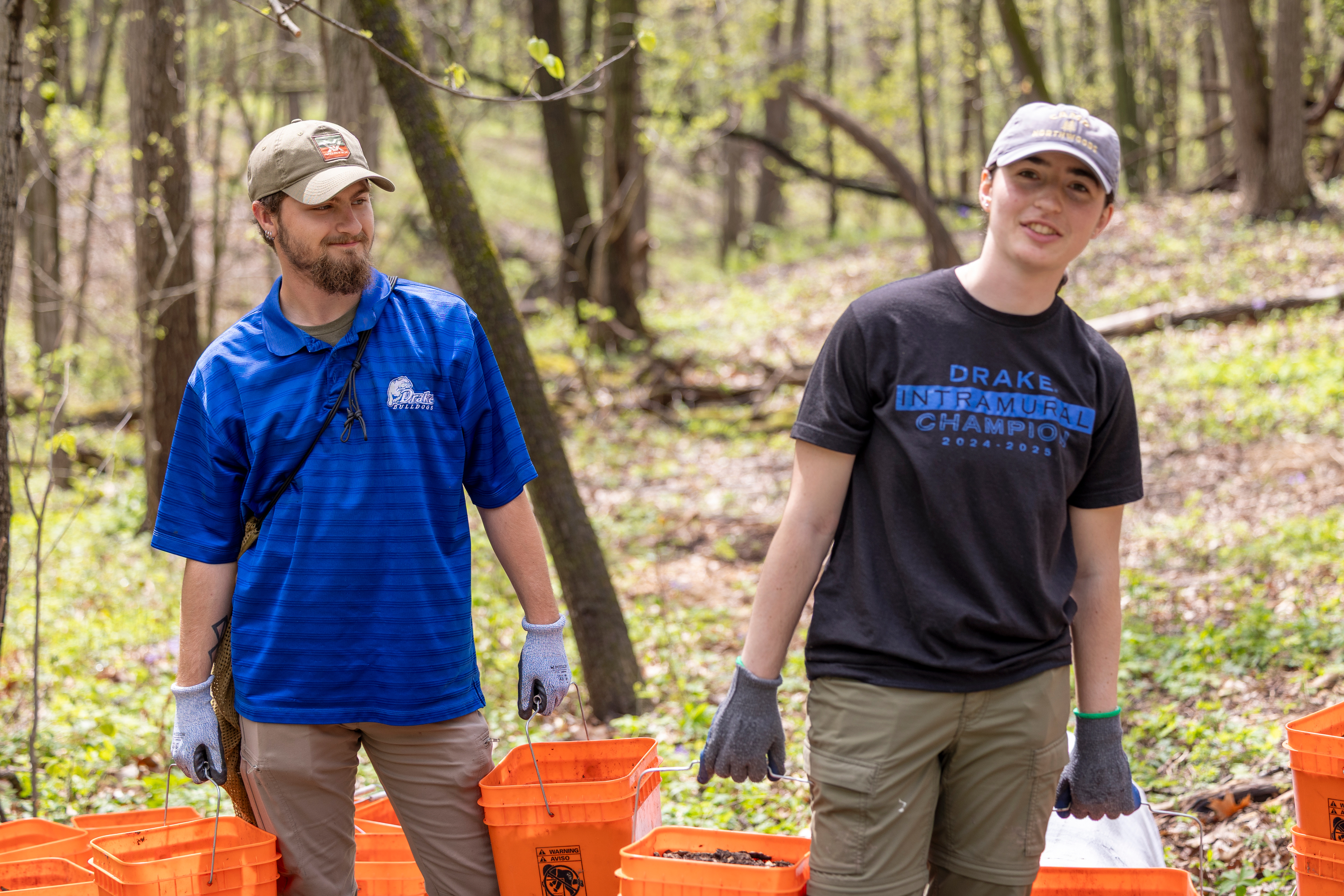 Drake students in ball caps and gloves move buckets of mulch during the Darling Tree Planting project