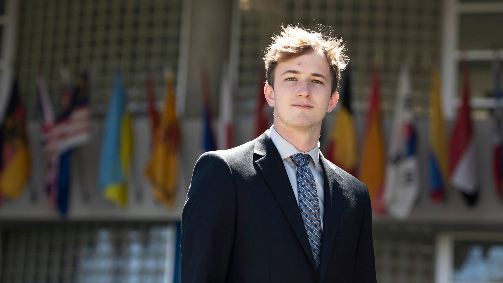 A student in business attire smiles at the camera