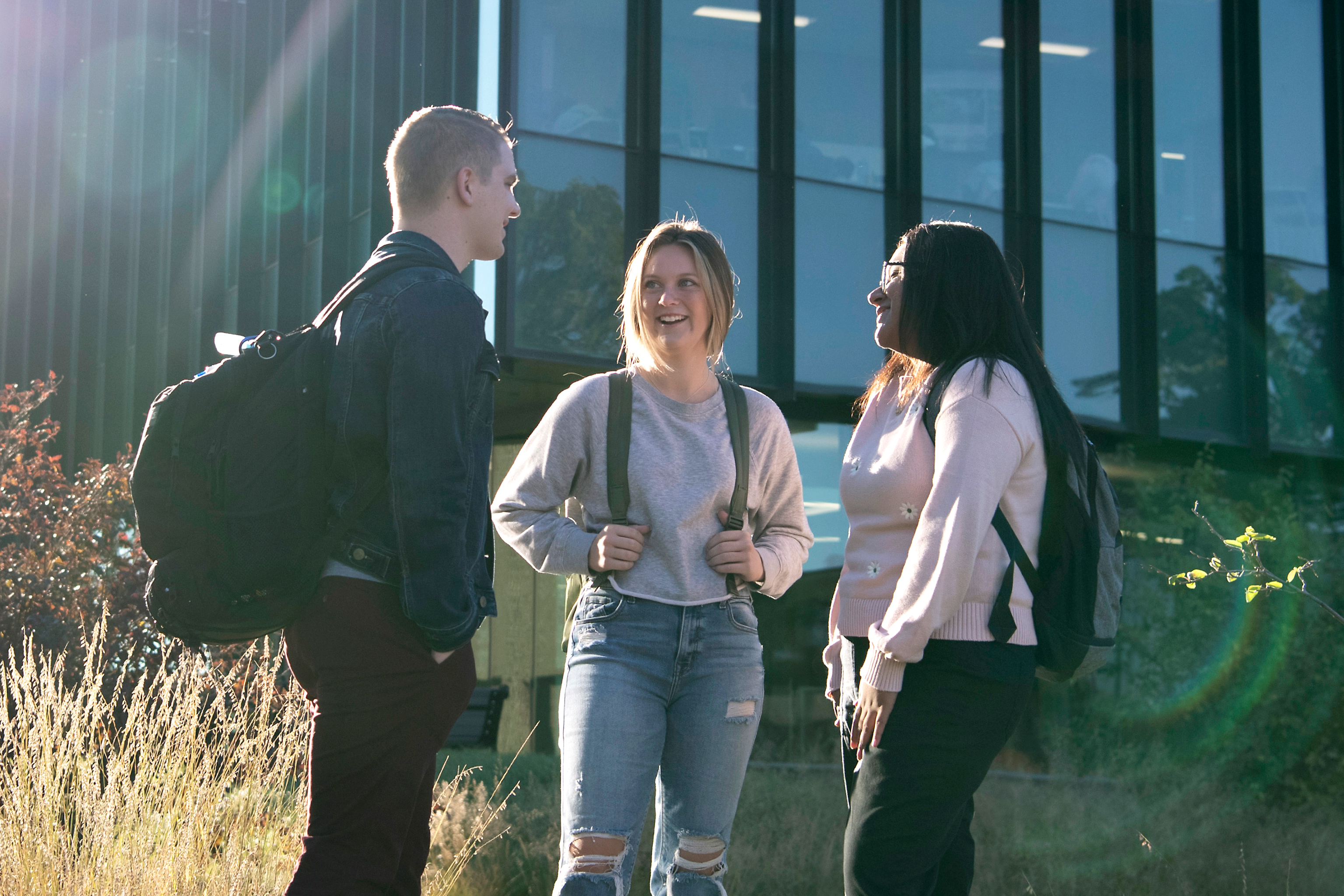 Three Drake students meet outside the School of Education building in a grassy area