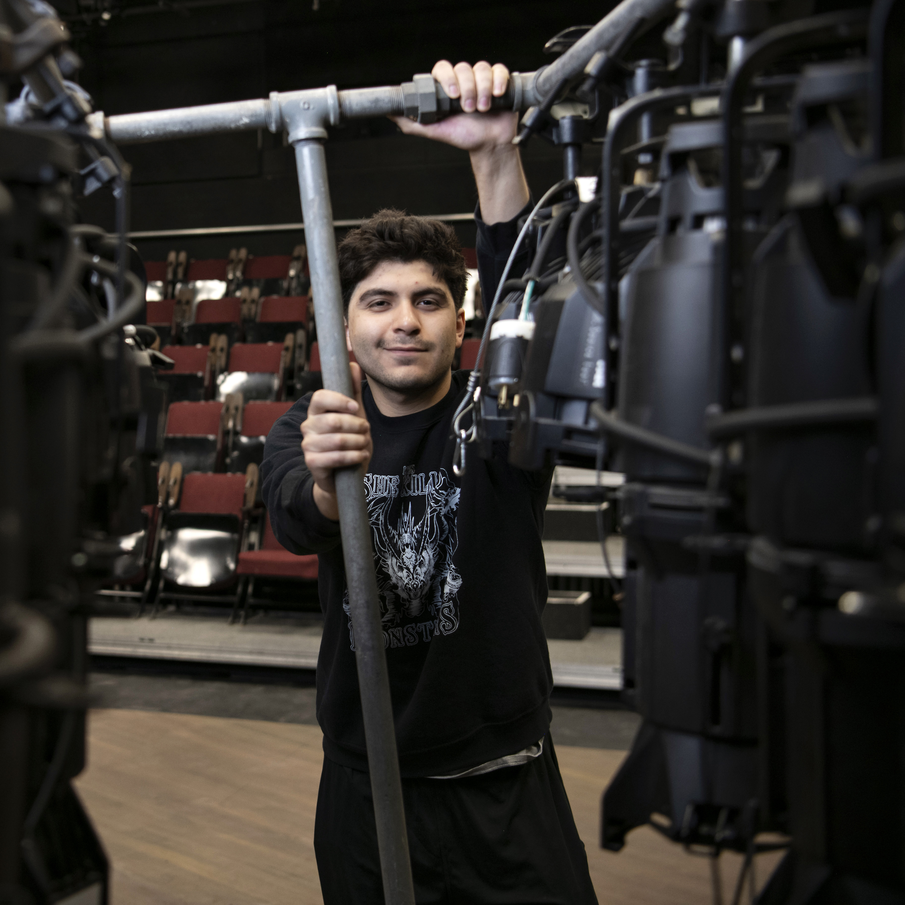 A Drake student adjusts a lighting rig in a campus performance space