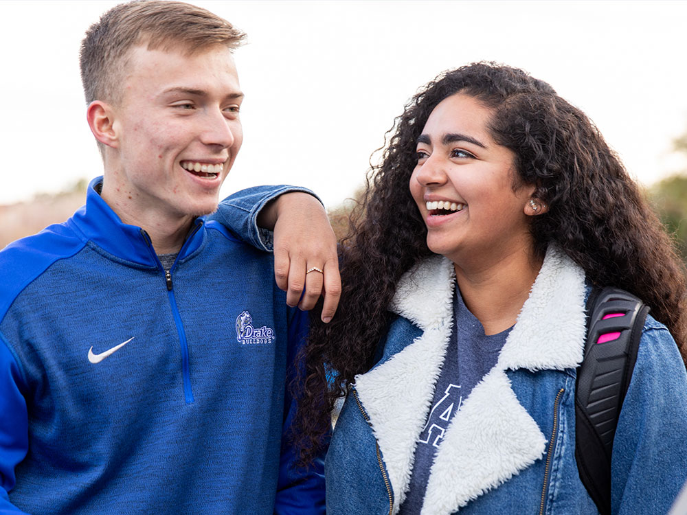Two drake students smiling together on Drake's campus near the agora.