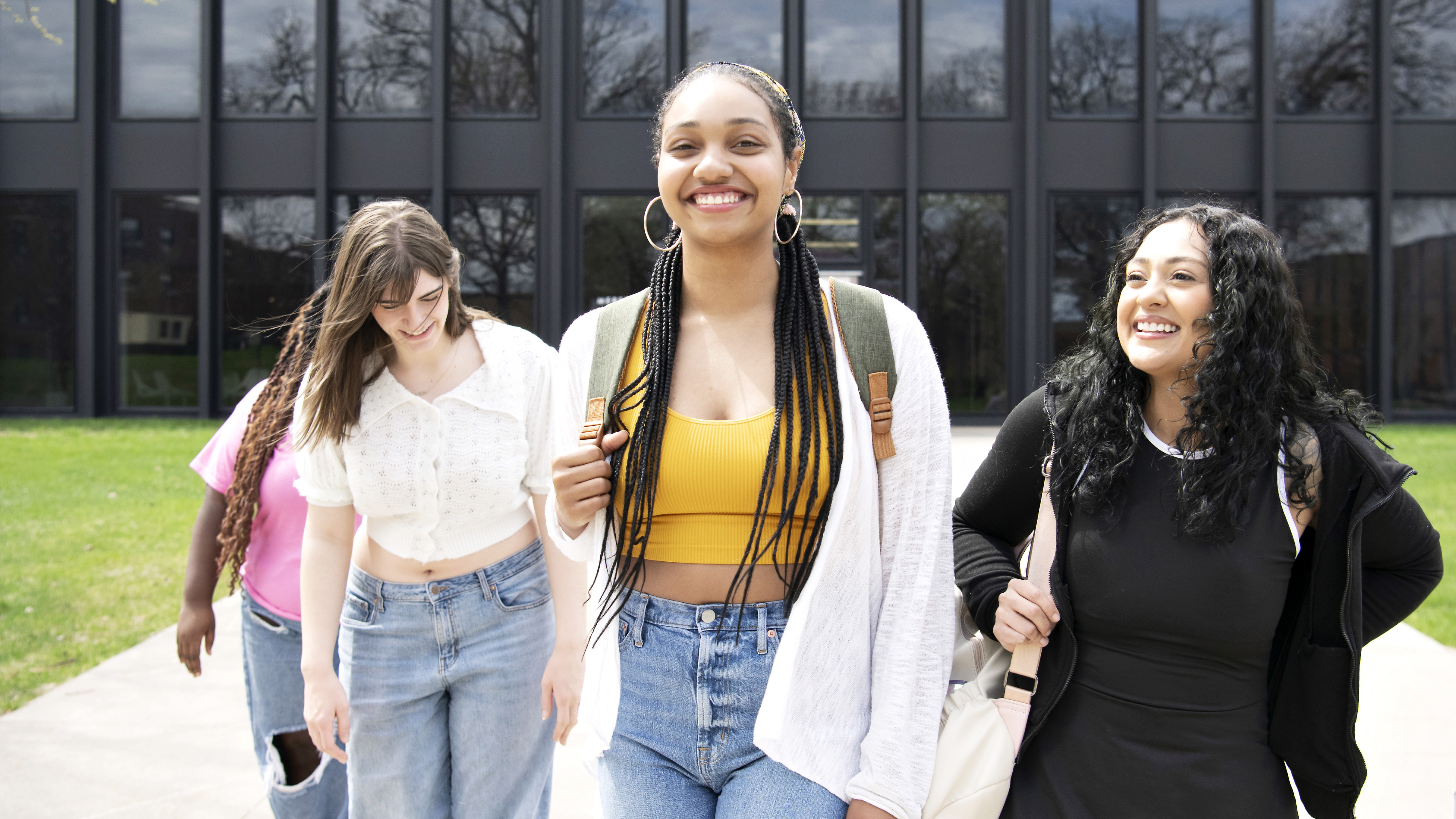 High school-aged students with backpacks depart a building on Drake's campus after participating in a post-secondary course