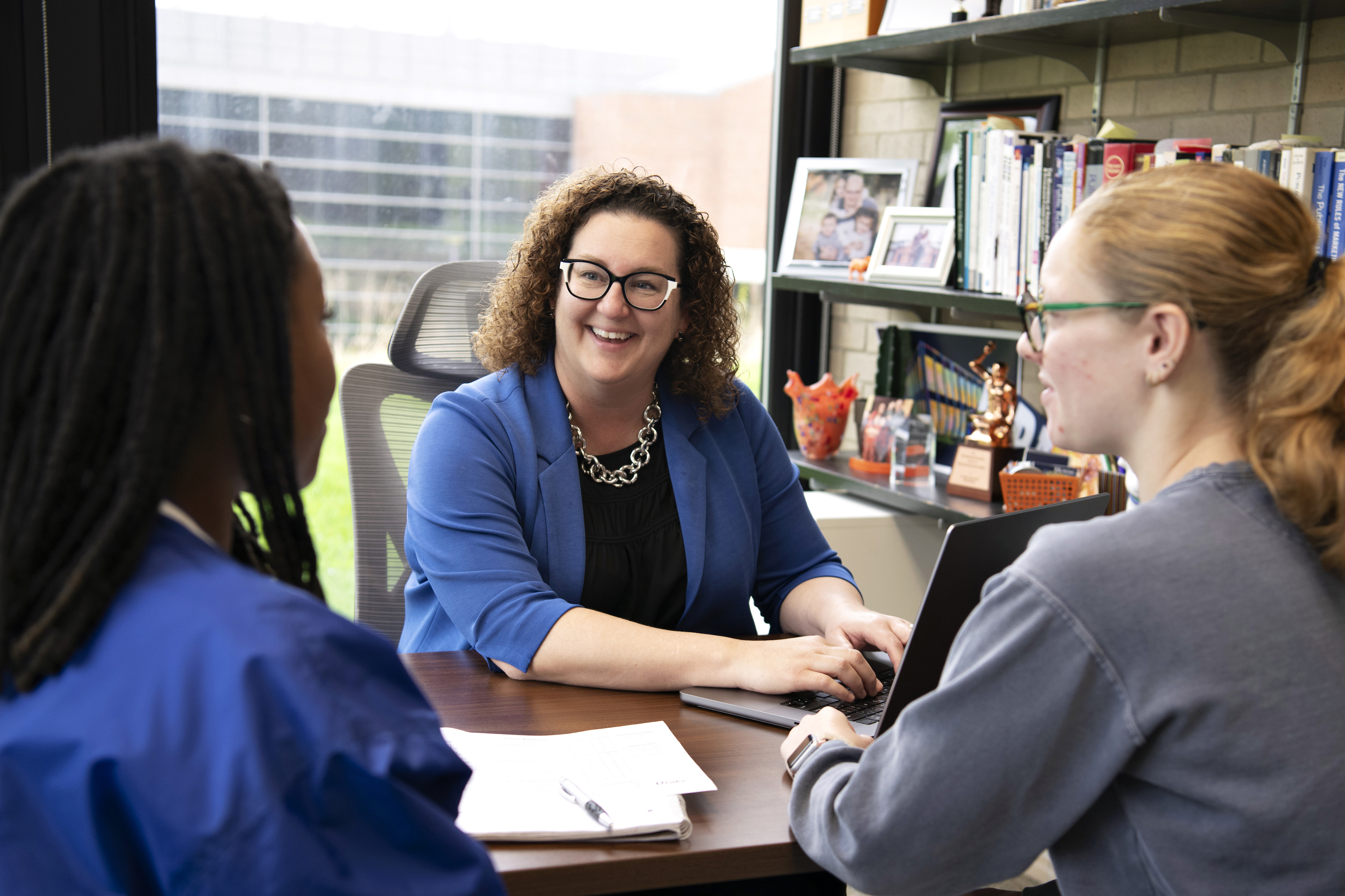 Around a desk, two Drake transfer students meet with an advisor to discuss getting involved on campus
