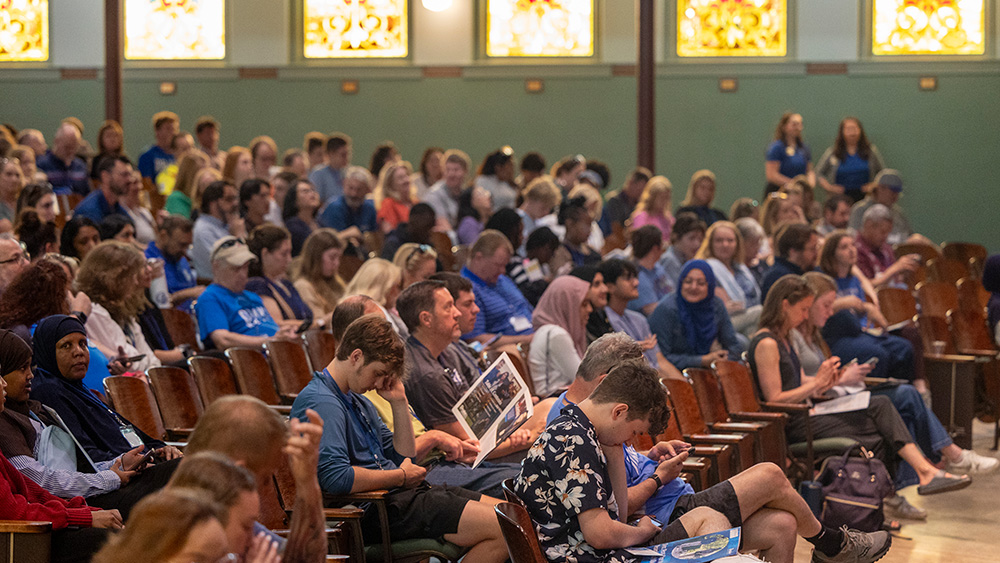 Wide angle view of a full auditorium of students, parents, and families in Sheslow during Summer Orientation.