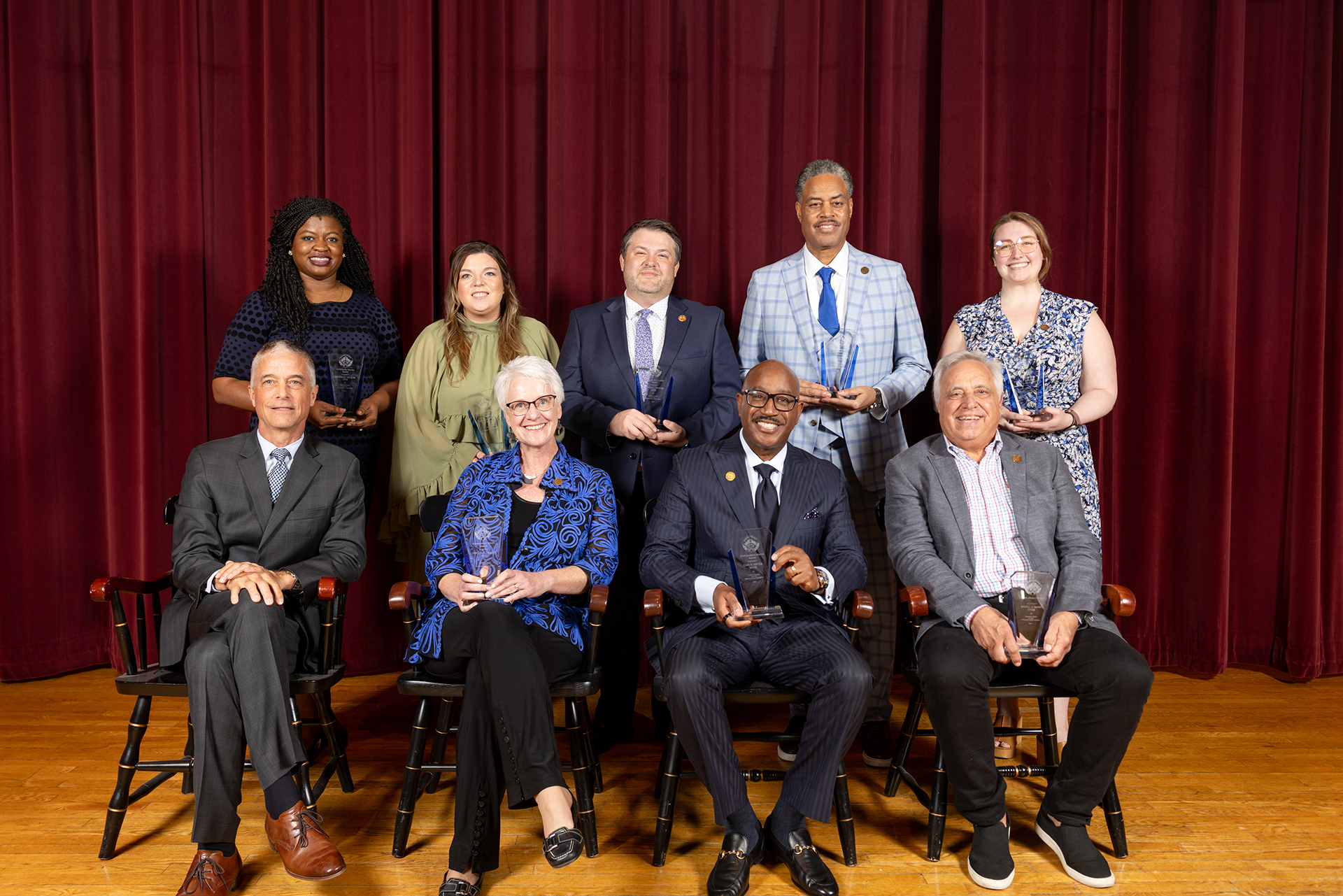 2026 Alumni Awards Winners seated on stage at the ceremony with Marty Martin, Drake University President.