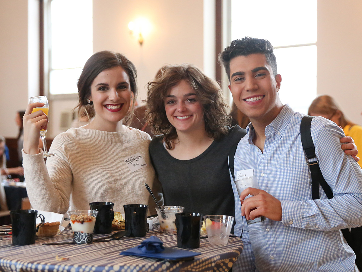 Drake alumni gather around a table to enjoy dessert and drinks during a campus event
