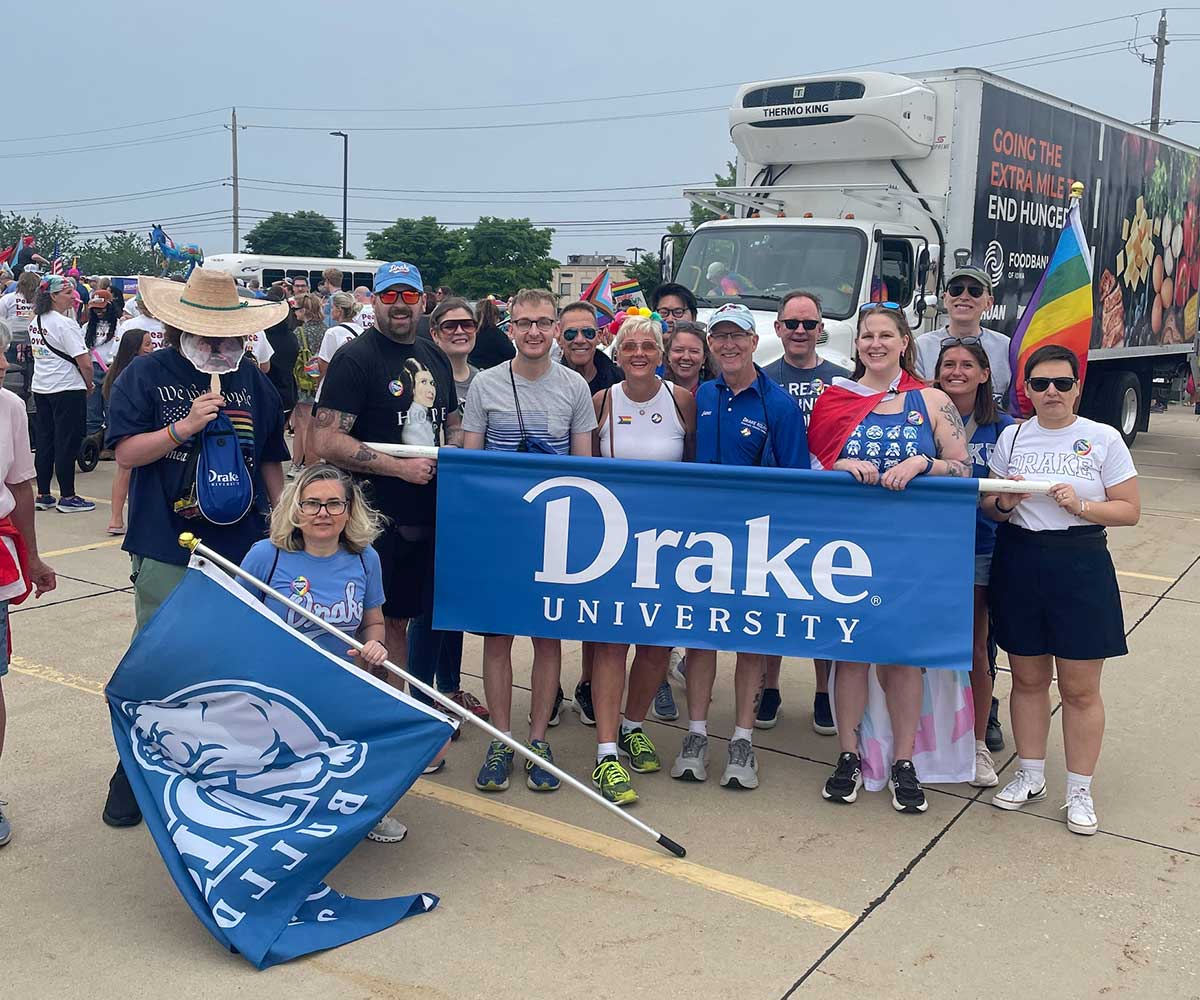 Group of Drake Alumni posing with a Drake University banner at the 2025 Pride Parade