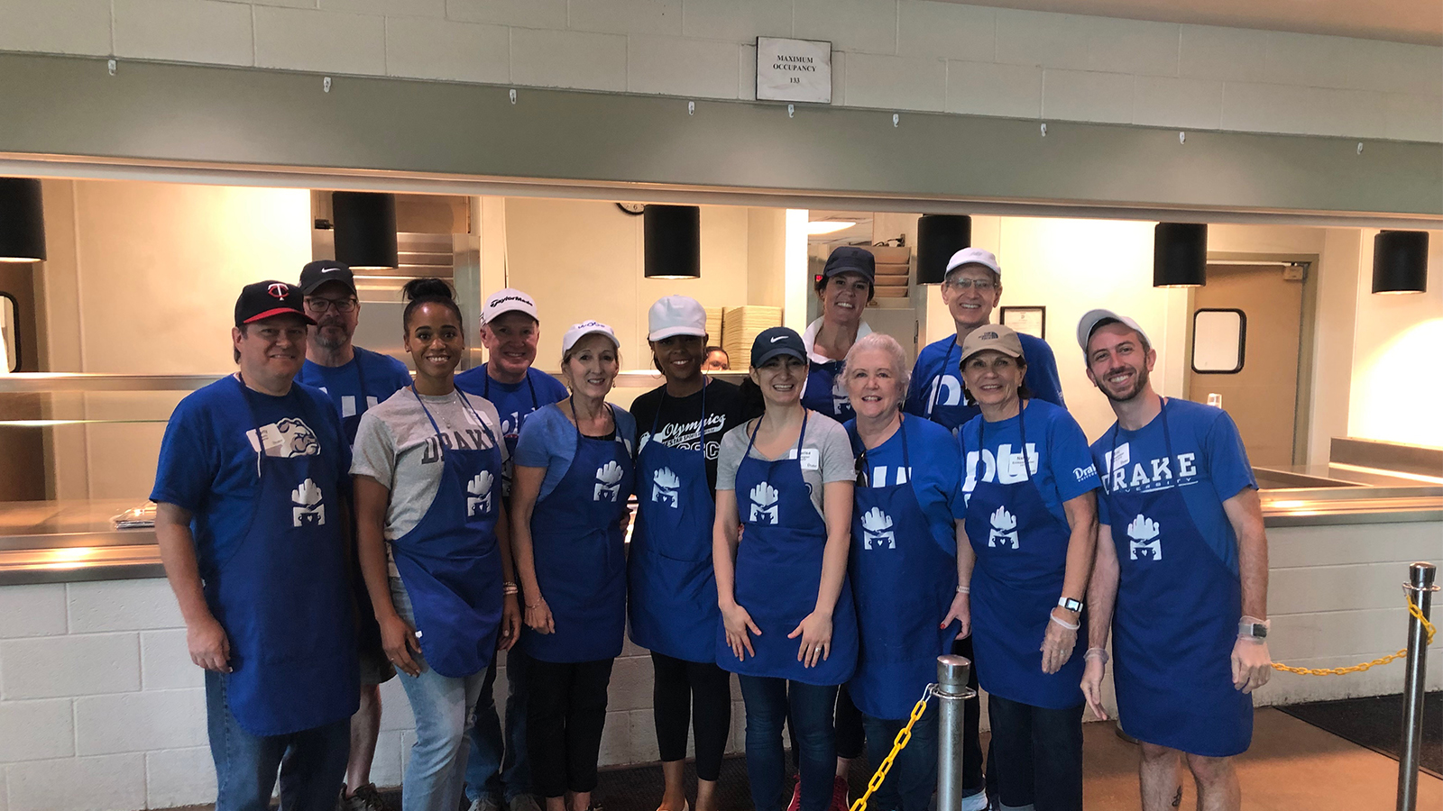 A group of Bulldog community members wearing blue aprons at a volunteer site