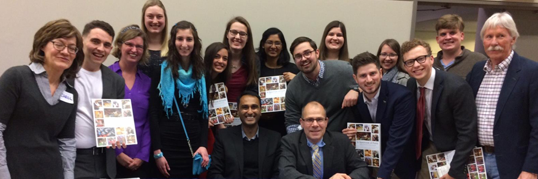 A large group of people standing smiling while holding copies of Drake Community Press