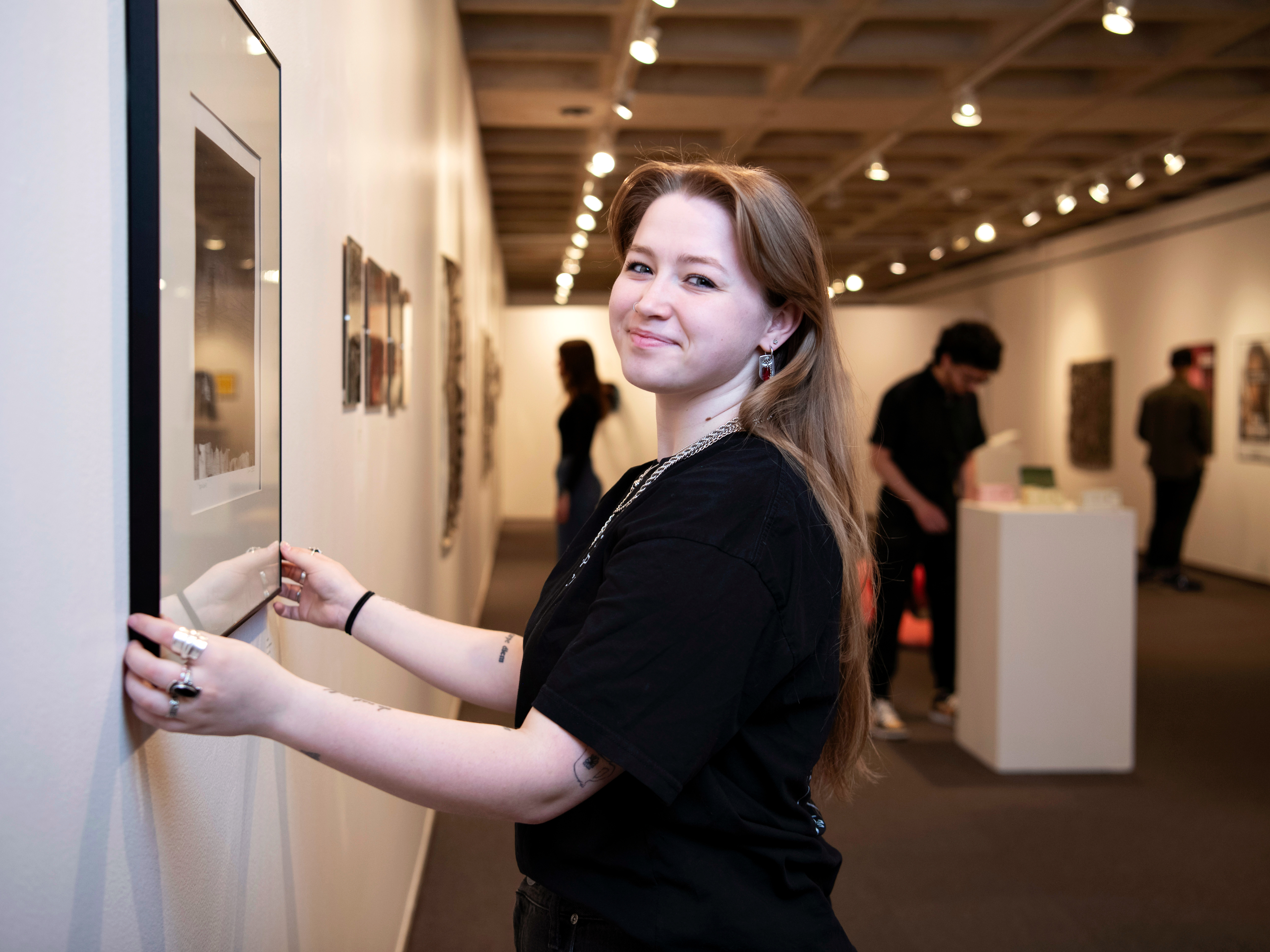 A student adjusts a painting ahead of an exhibit in one of Drake's art galleries