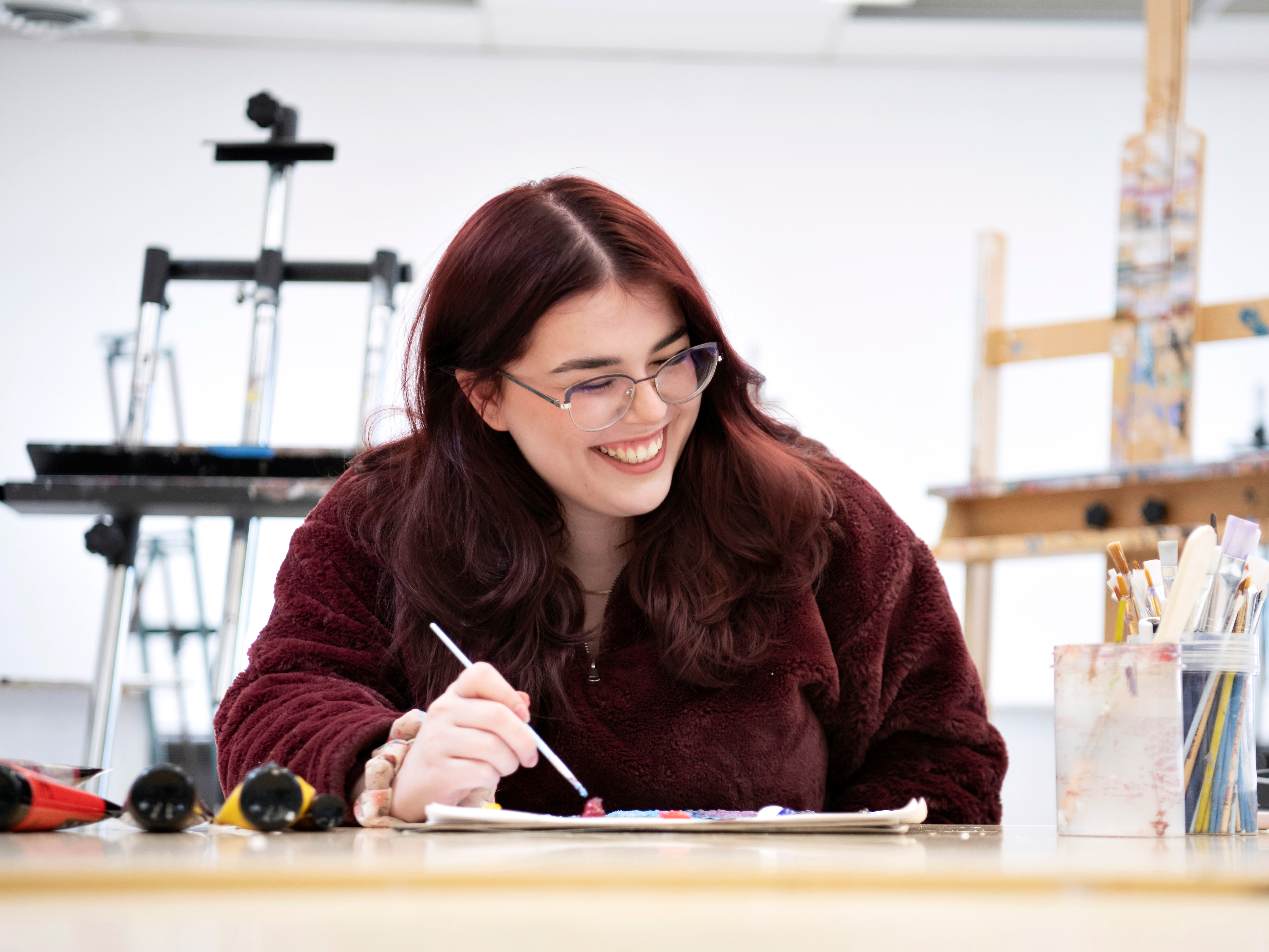 In one of Drake's art studios, a student smiles while working on a painting