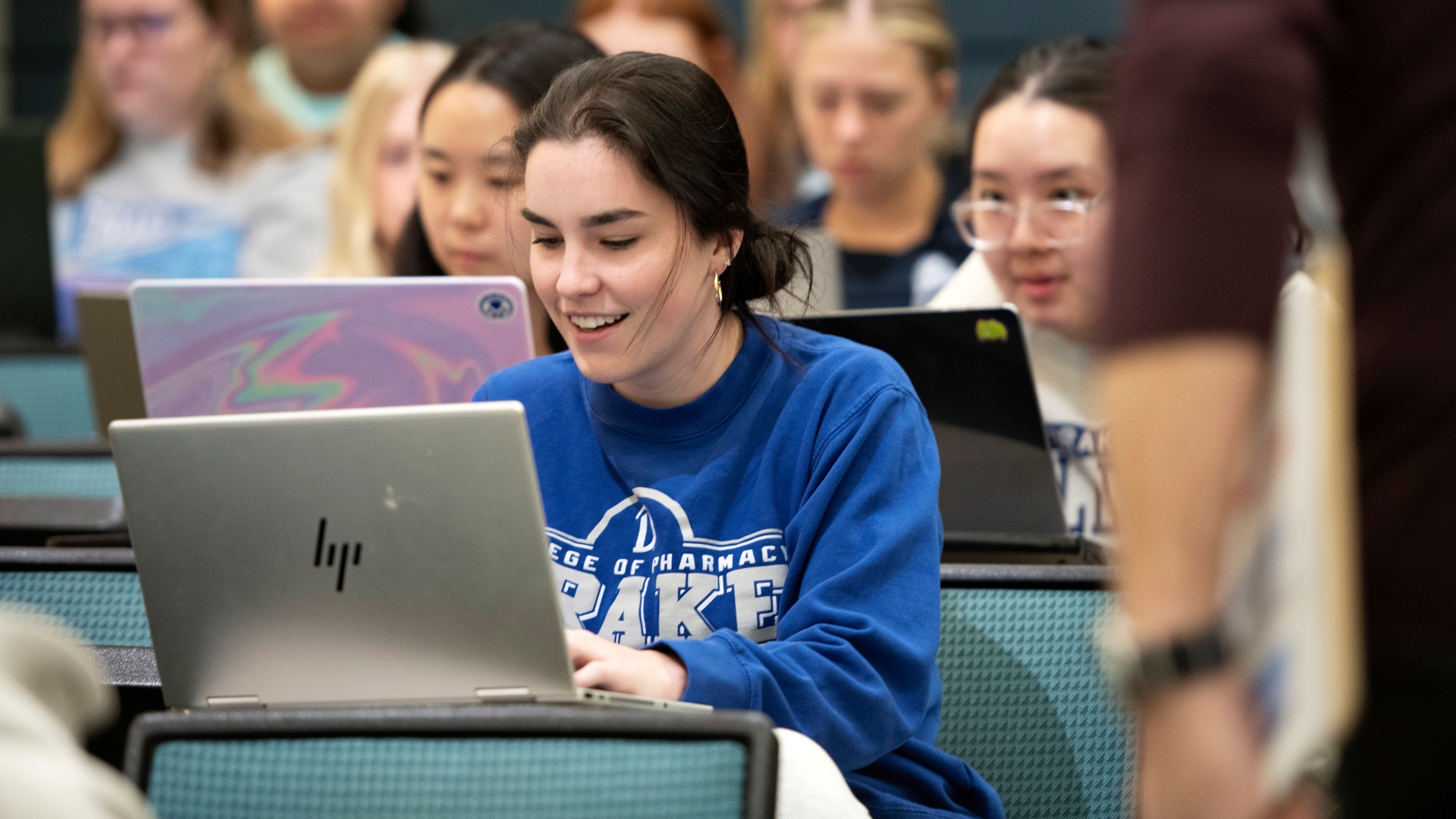 Female student in a lecture hall on her laptop