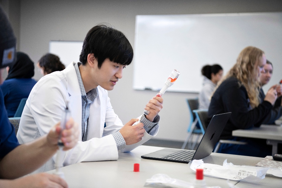 A Drake pharmacy student inserts medication into a syringe in lab