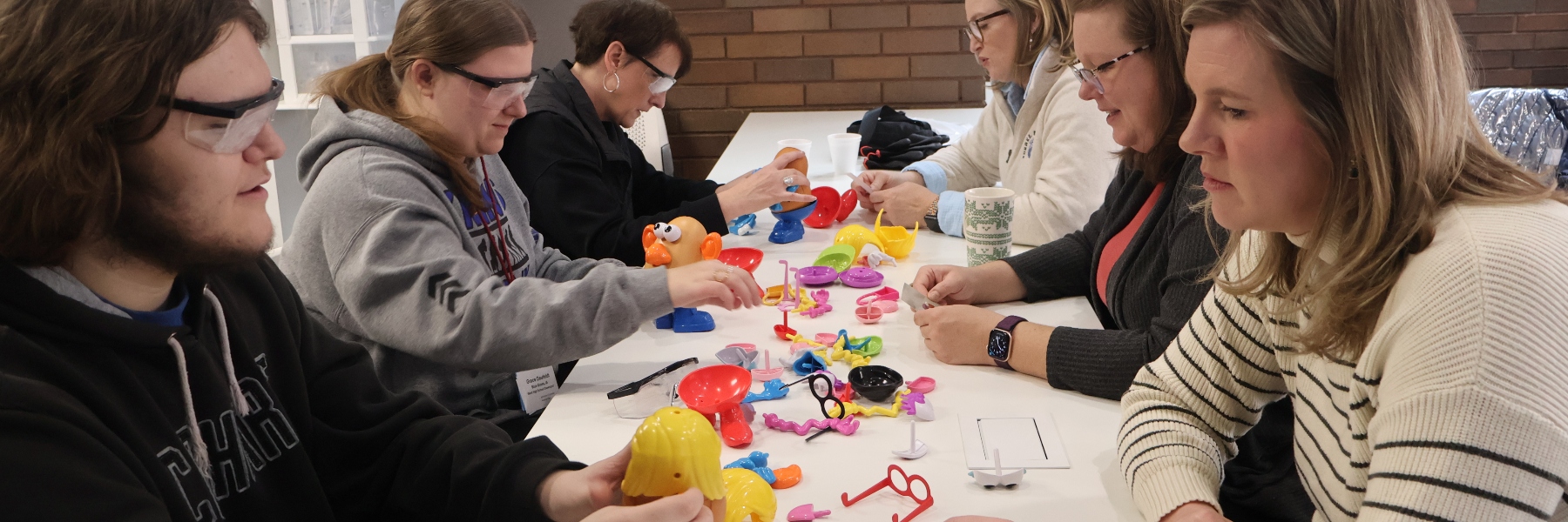 A group of admitted Drake students and their parents put together Mr Potato Heads with gloves and glasses on