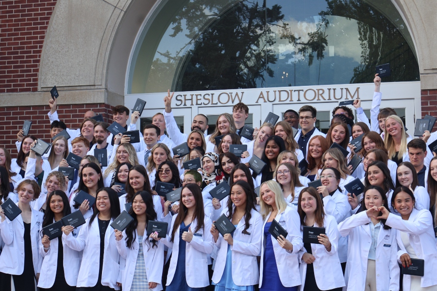 A large cohort of pharmacy students pose with their diplomas at the white coat ceremony