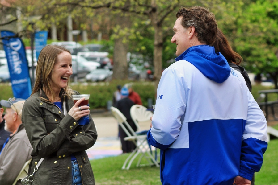 An alum and the Dean laugh and drink together at Drake Relays