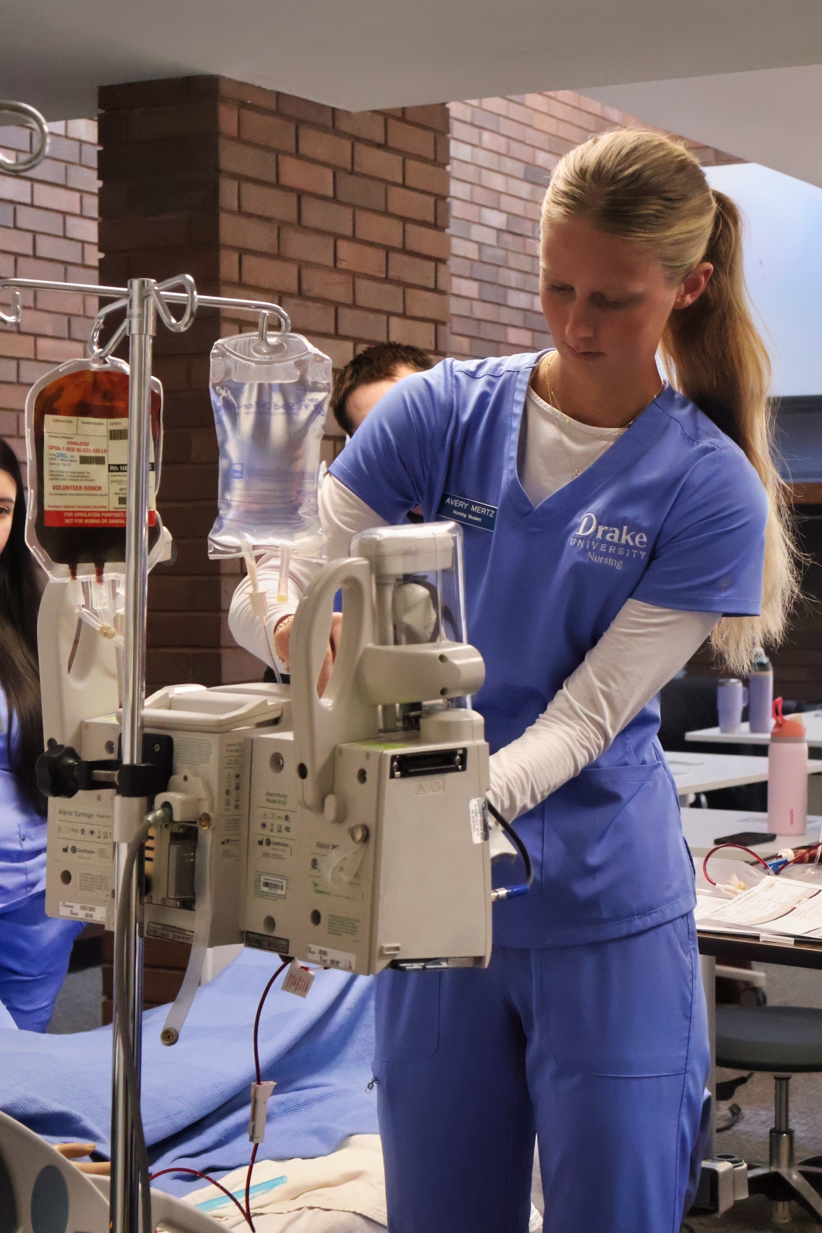 Avery Mertz hangs an IV bag in a nursing lab
