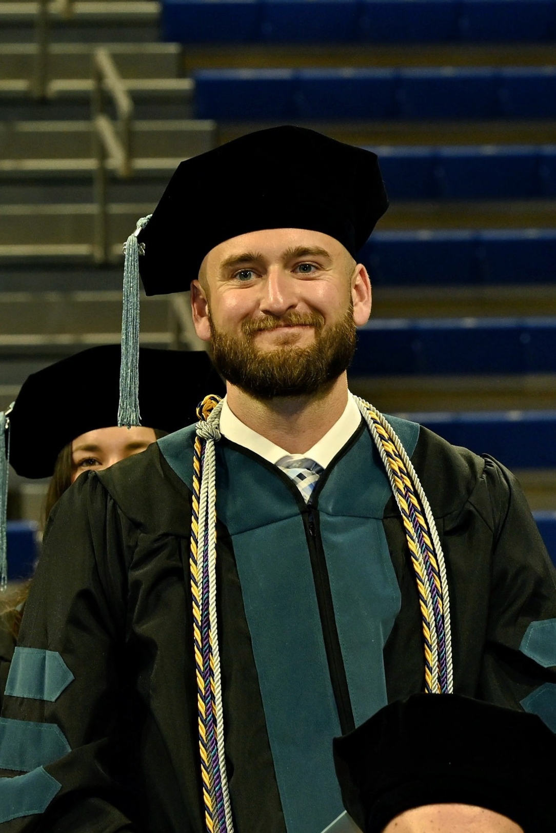 Cole Brockman in graduation regalia standing to receive an honor
