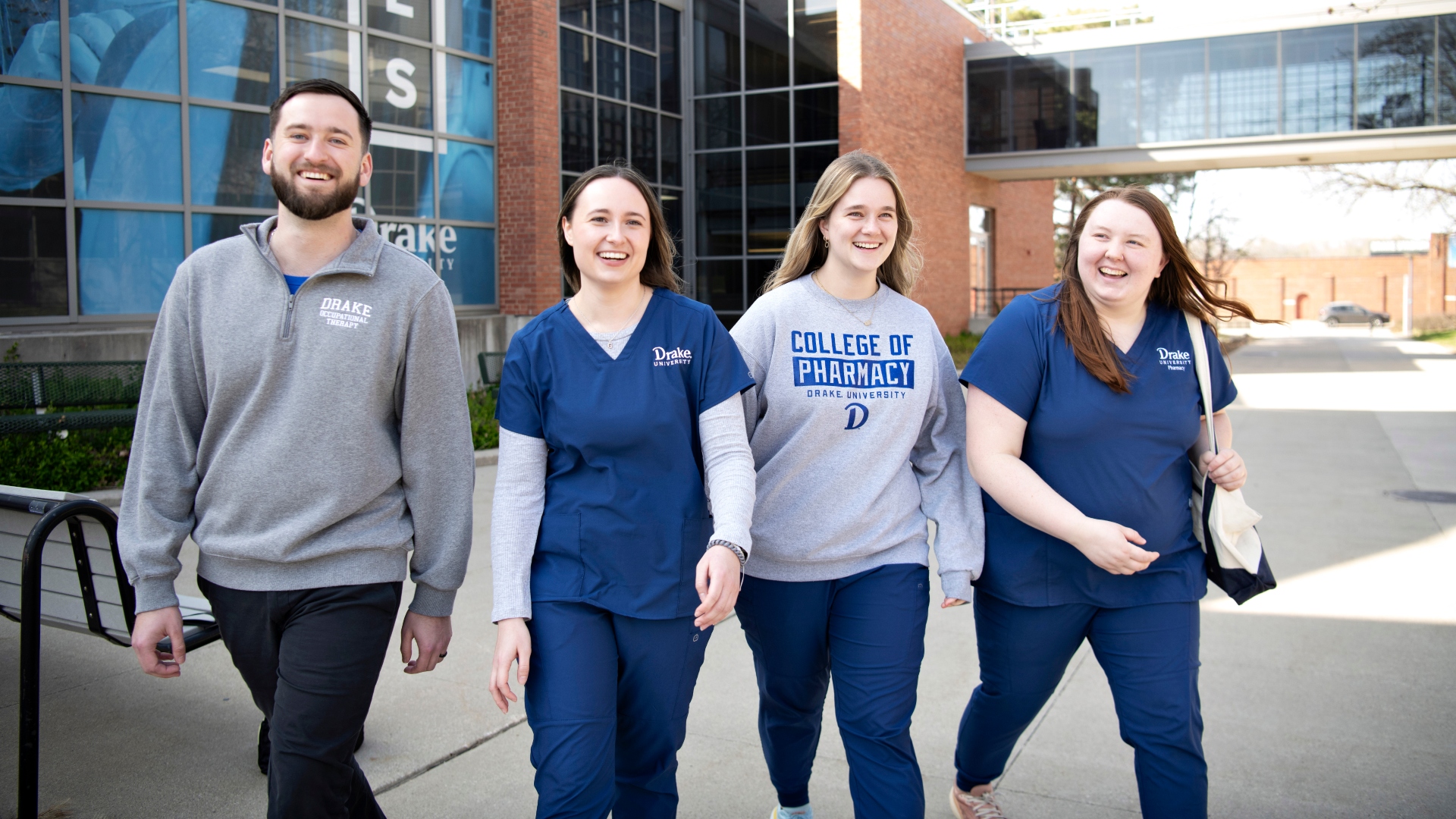 Four students in scrubs or sweatshirts depart Drake University's College of Pharmacy and Health Sciences