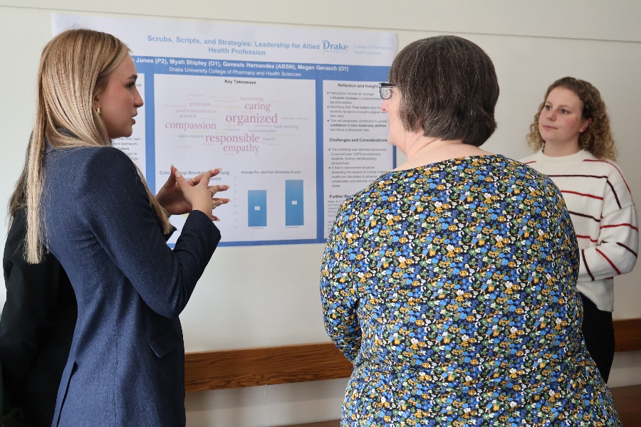A Drake student and her classmate present a research poster to a professor
