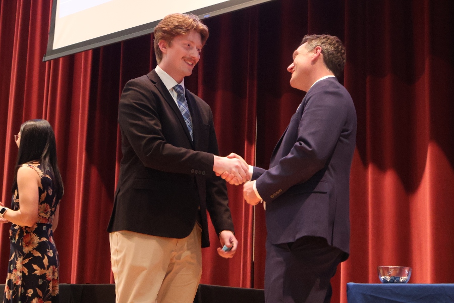 A Drake student walks across the stage and shakes the hand of the Dean as he accepts his pin and name tag