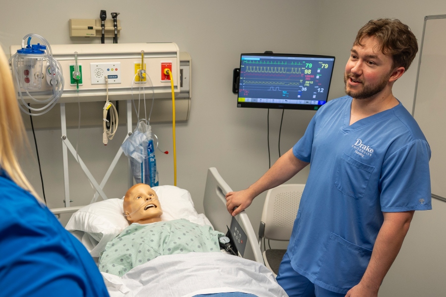 A Drake nursing student attends to a mannequin in a medical exam room
