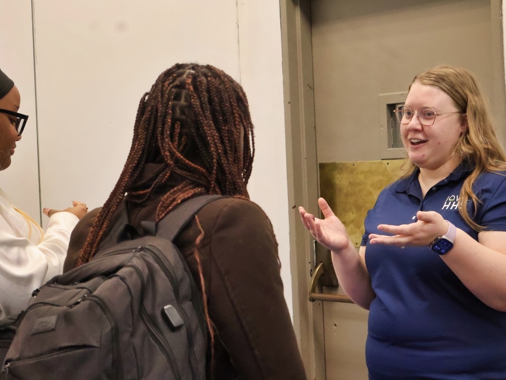 An Iowa Health Services employee chats with two Drake students