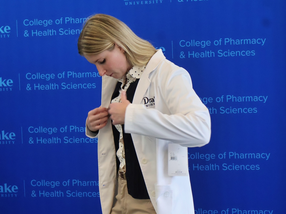 A Drake Pre-Pharmacy student in professional dress tries on a white coat at her interview day