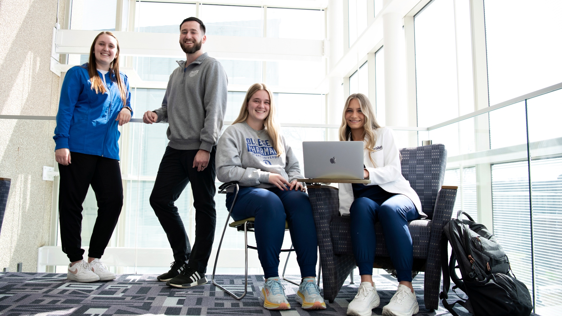 Four health professions students pose together in a study room with two students sharing a laptop