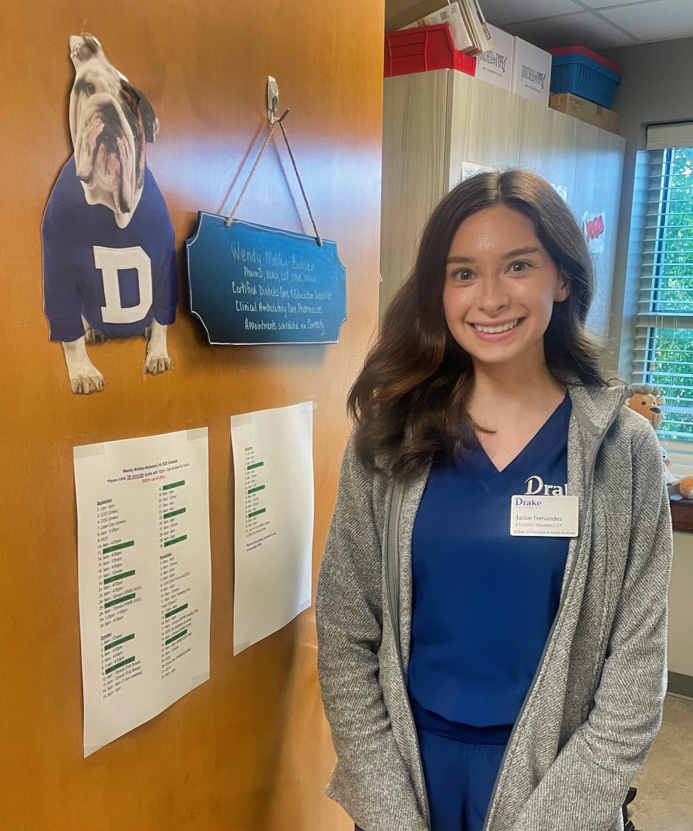 Jackie Fernandez in scrubs posing in the doorway of a Wendy Mobley-Bukstein's office decorated with Drake memorabilia