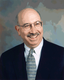 Professional headshot of Jerry Karbeling in a suit and tie with glasses.