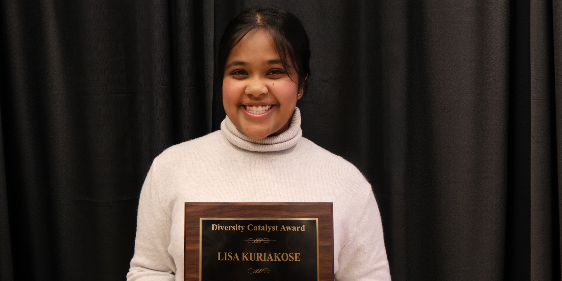 Lisa Kuriakose poses with her Diversity Catalyst Award plaque