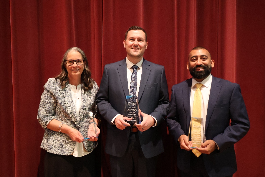Three CPHS alumni stand on a stage holding awards
