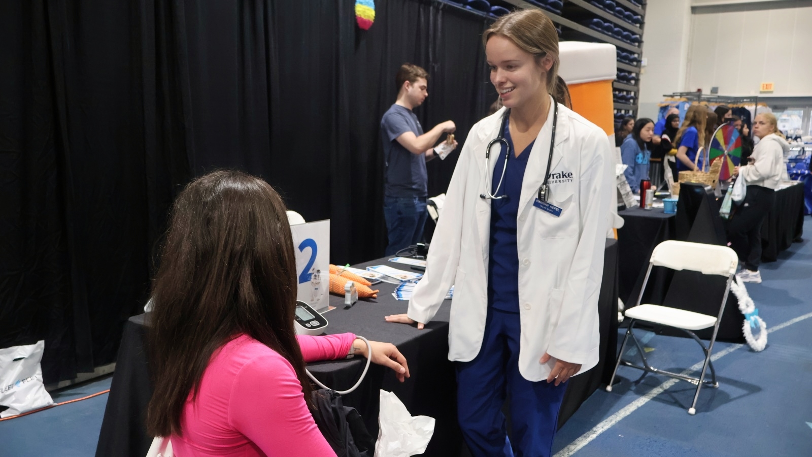 Drake pharmacy student takes a blood pressure reading at a Drake Relays event
