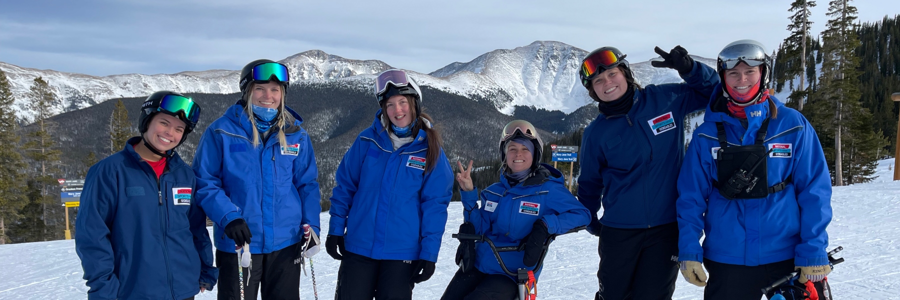 Drake OT capstone student poses with a group of skiers on top of a mountain
