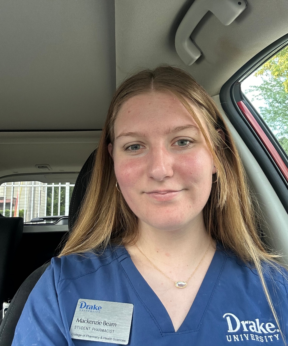 Selfie of Mackenzie Beam in her car wearing her Drake scrubs and nametag
