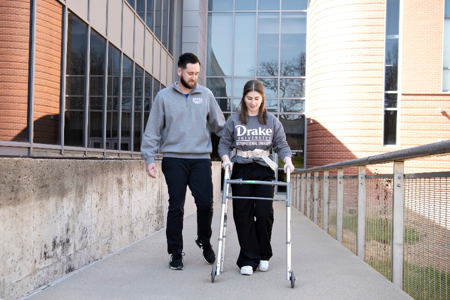 Student helps another student walk using a walker and gait belt