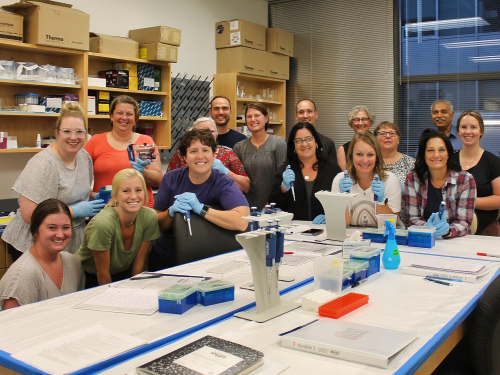 A group of Drake students and faculty and Iowa educators pose together in a pharmacogenomics lab