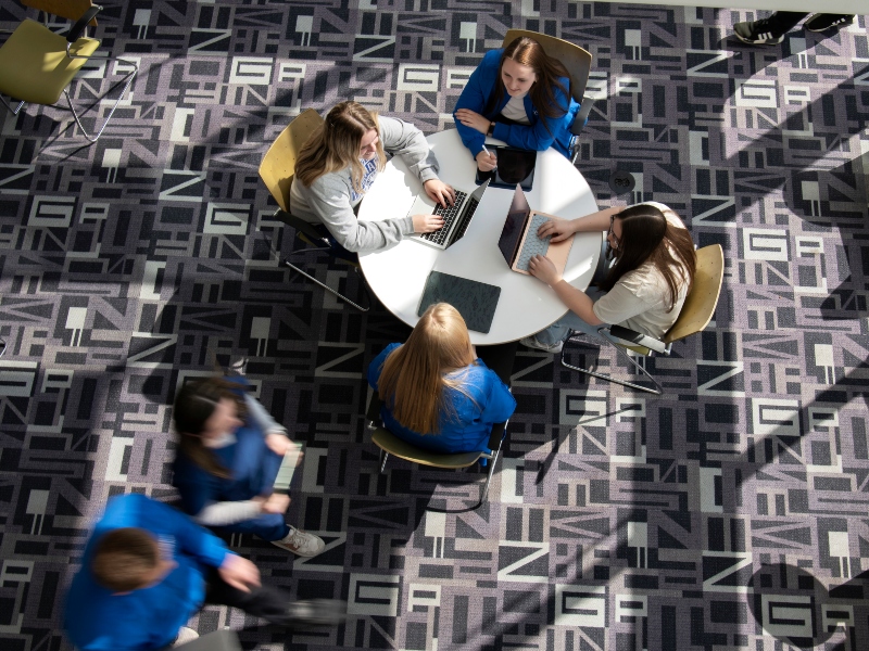 Birdseye view of students at a table studying as other students walk by