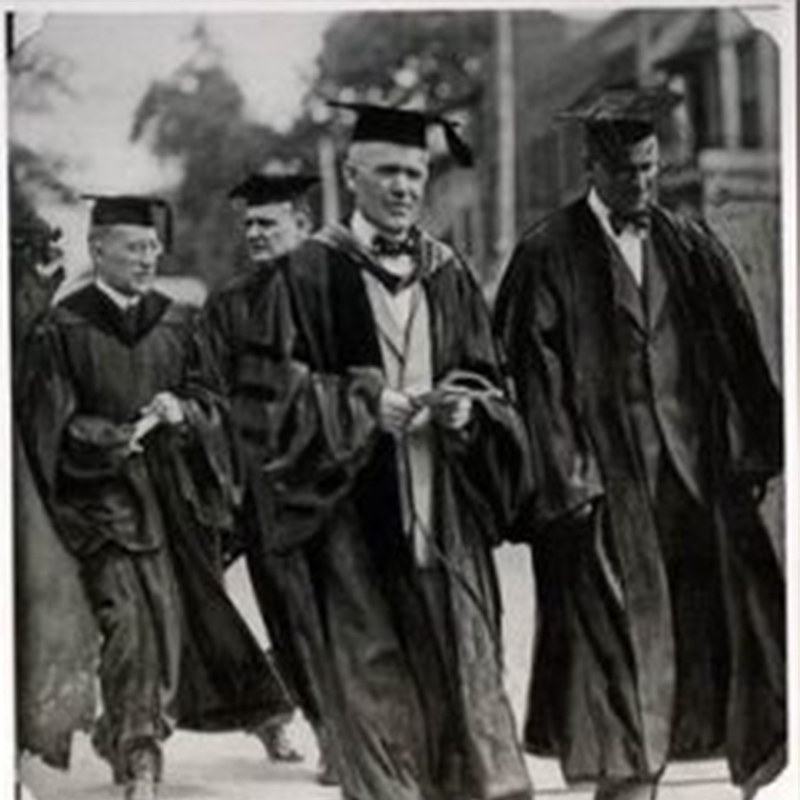 Black-and-white photo of Jay N. Darling in graduation regalia walking outdoors during a graduation procession.