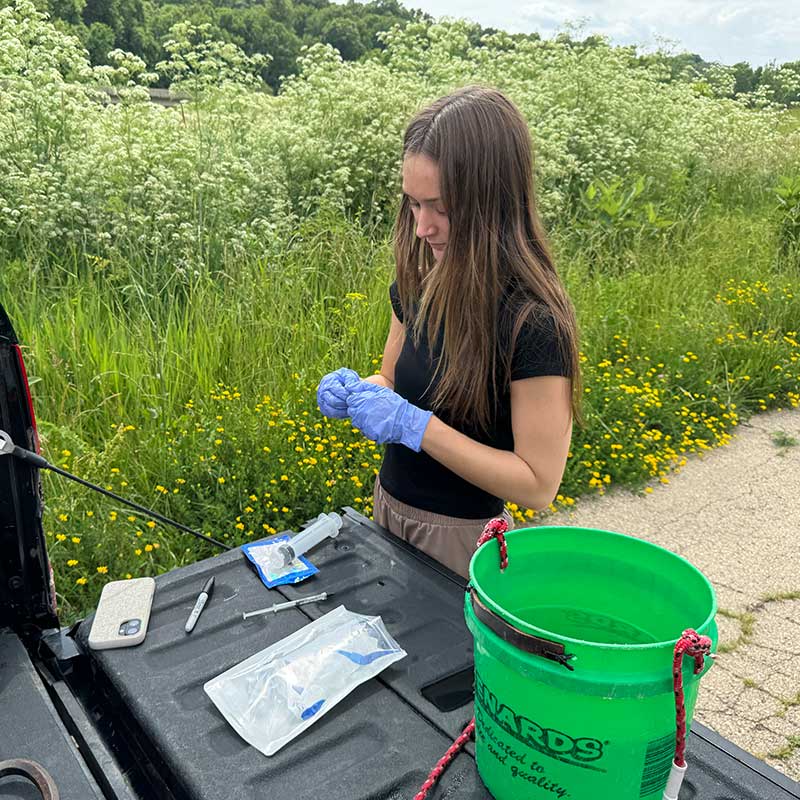 Paige Robertson performing water testing at the back of a truck.