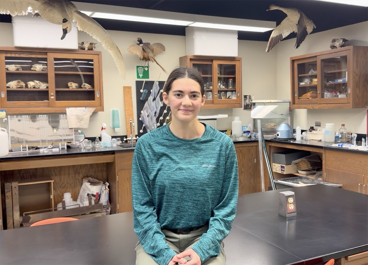 Macy Gardner sitting on a table in a conservation lab at Drake University.