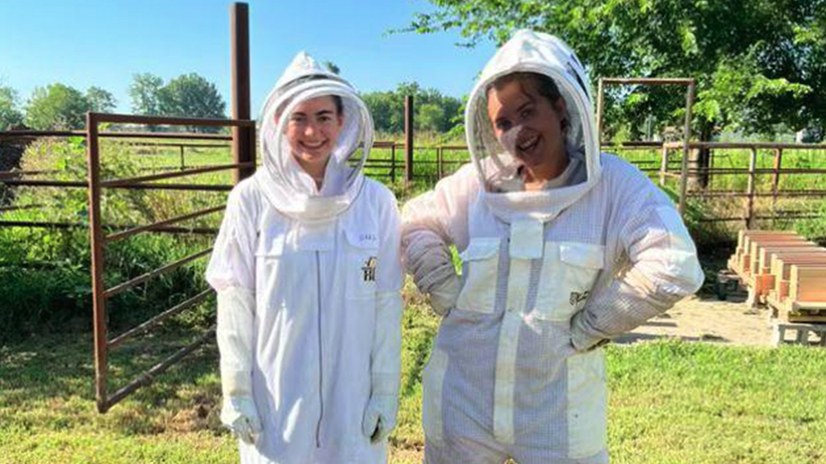 Two students in Quapaw Nation in white protective suits smiling.