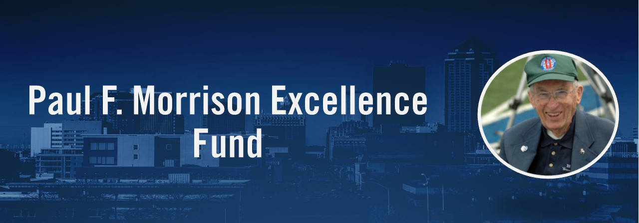 Banner with a blue-tinted city skyline background and the text “Paul F. Morrison Excellence Fund,” plus a circular photo of Paul F. Morrison in a green cap smiling.